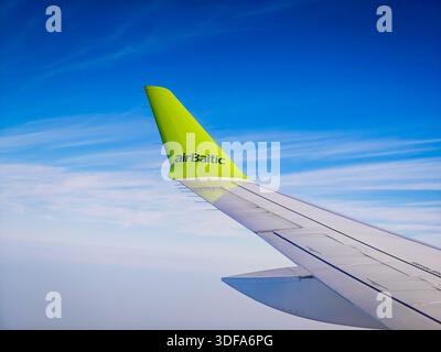 01 11 2026 - Dubai, Vereinigte Arabische Emirate. Der Blick aus dem Flugzeugfenster von airBaltic Airlines während eines Fluges. Flugzeugflügel vor blauem Himmel Stockfoto
