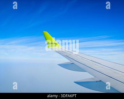 01 11 2026 - Dubai, Vereinigte Arabische Emirate. Der Blick aus dem Flugzeugfenster von airBaltic Airlines während eines Fluges. Flugzeugflügel vor blauem Himmel Stockfoto