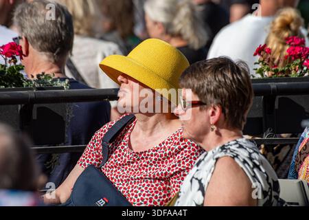 Frau mit gelbem, glockenförmigem Krempenhut auf der Terrasse des Restaurants Kappeli im Esplanadi Park, Helsinki, Finnland Stockfoto