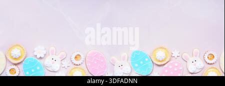 Back-Bodenrand mit Ostermotiv oder Frühlingsmotiv mit verschiedenen Keksen und süßen Desserts. Ansicht von oben nach unten auf einem rosafarbenen Steinbannerhintergrund mit Kopierraum Stockfoto