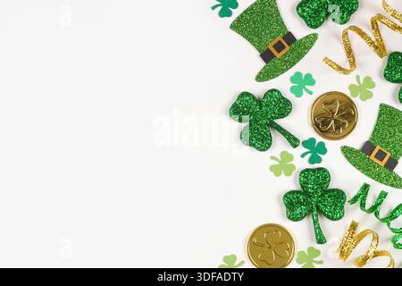 Am St. Patricks Day gibt es einen Rand aus grünen Schamfelsen, Leprechaun-Hüten, Goldmünzen und Band. Ansicht über weißem Hintergrund mit Kopierraum. Stockfoto