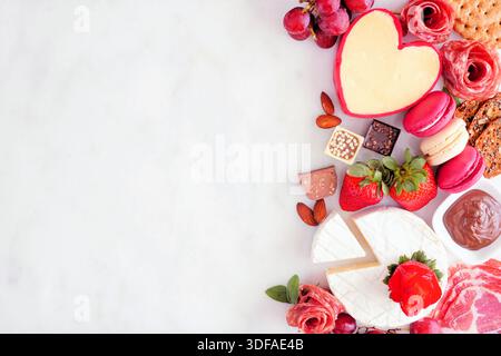 Valentinstag-Thema Wurstwaren seitlich am Rand. Blick von oben vor weißem Marmorhintergrund. Kopierbereich. Stockfoto
