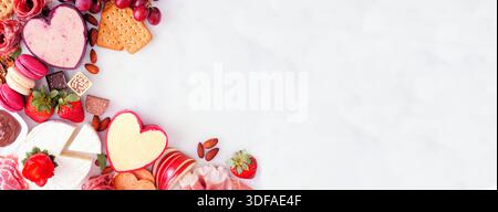 Valentinstag-Thema Wurstwaren-Eckrand. Blick von oben nach unten über einen weißen Marmorbanner Hintergrund. Kopierbereich. Stockfoto