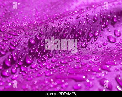 Violettes, wasserdichtes Material mit Wassertropfen aus nächster Nähe Stockfoto