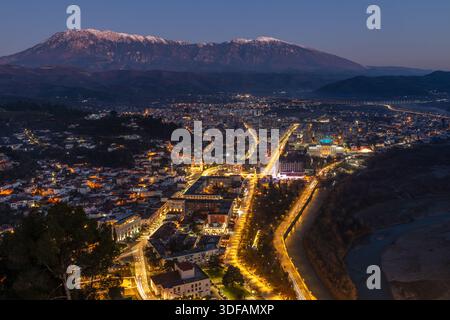 Nächtliche Stadtlandschaft mit modernen Wohngebäuden, beleuchteten Straßen, dichtem Stadtkern und schneebedeckten Gipfeln, Berat, Albanien Stockfoto