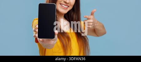 Abgeschnitten von einer jungen Frau, die ein Smartphone mit leerem Bildschirm zeigt Stockfoto