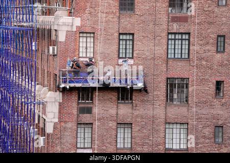 Arbeiter an Gerüsten, die Ziegelfassaden umdeuten, defekte Ziegelsteine und Mörtel entfernen, wie es das New York City Local Law 11 vorschreibt, das Reparaturen, regelmäßige Inspektionen und Wartung von Gebäudefassaden verlangt, Freitag, 31. Oktober 2025. Foto: Jennifer Graylock-Alamy Stockfoto