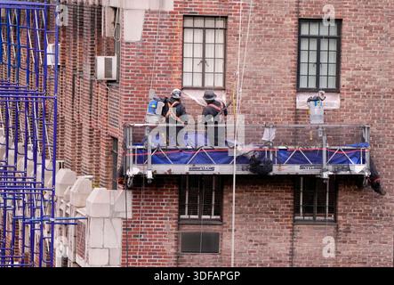Arbeiter an Gerüsten, die Ziegelfassaden umdeuten, defekte Ziegelsteine und Mörtel entfernen, wie es das New York City Local Law 11 vorschreibt, das Reparaturen, regelmäßige Inspektionen und Wartung von Gebäudefassaden verlangt, Freitag, 31. Oktober 2025. Foto: Jennifer Graylock-Alamy Stockfoto