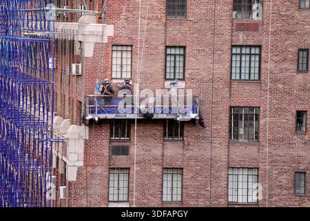 Arbeiter an Gerüsten, die Ziegelfassaden umdeuten, defekte Ziegelsteine und Mörtel entfernen, wie es das New York City Local Law 11 vorschreibt, das Reparaturen, regelmäßige Inspektionen und Wartung von Gebäudefassaden verlangt, Freitag, 31. Oktober 2025. Foto: Jennifer Graylock-Alamy Stockfoto