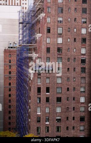 Arbeiter an Gerüsten, die Ziegelfassaden umdeuten, defekte Ziegelsteine und Mörtel entfernen, wie es das New York City Local Law 11 vorschreibt, das Reparaturen, regelmäßige Inspektionen und Wartung von Gebäudefassaden verlangt, Freitag, 31. Oktober 2025. Foto: Jennifer Graylock-Alamy Stockfoto
