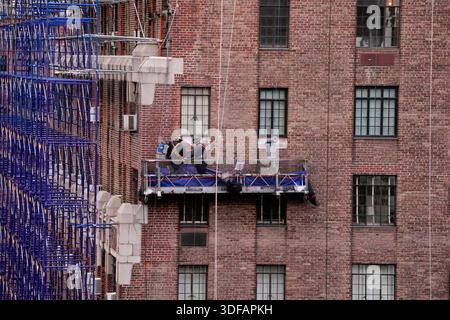 Arbeiter an Gerüsten, die Ziegelfassaden umdeuten, defekte Ziegelsteine und Mörtel entfernen, wie es das New York City Local Law 11 vorschreibt, das Reparaturen, regelmäßige Inspektionen und Wartung von Gebäudefassaden verlangt, Freitag, 31. Oktober 2025. Foto: Jennifer Graylock-Alamy Stockfoto