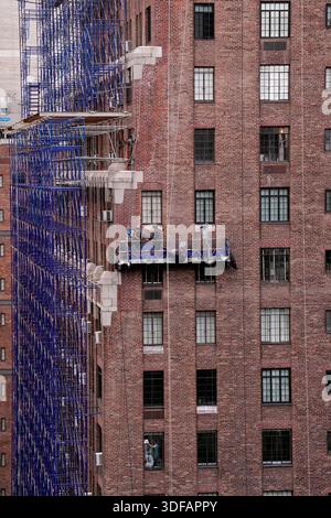 Arbeiter an Gerüsten, die Ziegelfassaden umdeuten, defekte Ziegelsteine und Mörtel entfernen, wie es das New York City Local Law 11 vorschreibt, das Reparaturen, regelmäßige Inspektionen und Wartung von Gebäudefassaden verlangt, Freitag, 31. Oktober 2025. Foto: Jennifer Graylock-Alamy Stockfoto