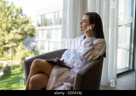 Ziemlich langhaarige junge Frau, die Musik hört und friedlich aussieht Stockfoto