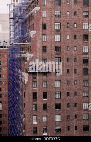 Arbeiter an Gerüsten, die Ziegelfassaden umdeuten, defekte Ziegelsteine und Mörtel entfernen, wie es das New York City Local Law 11 vorschreibt, das Reparaturen, regelmäßige Inspektionen und Wartung von Gebäudefassaden verlangt, Freitag, 31. Oktober 2025. Foto: Jennifer Graylock-Alamy Stockfoto