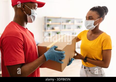 Afrikanische Frau Nimmt Kartonpaket Von Einem Zusteller, Der Zu Hause Steht Stockfoto