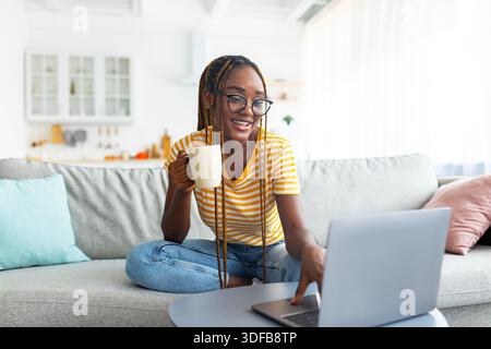 Schöne schwarze Frau, die online nach Filmen sucht Stockfoto