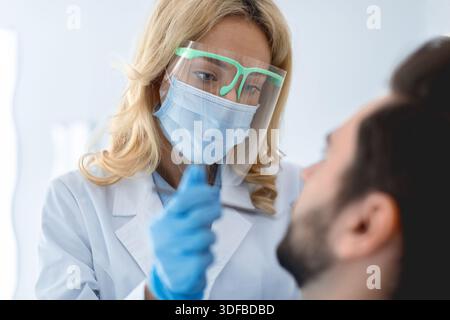 Weibliche Zahnärztin in Gesichtsmaske und Schutzbrille, die Behandlung Stockfoto