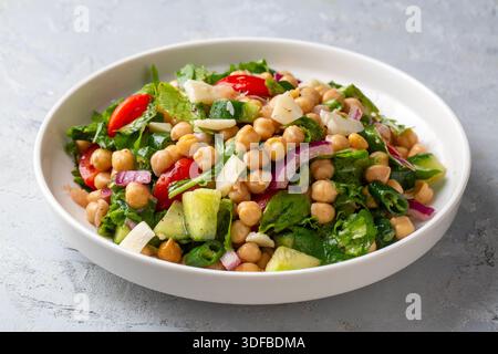 Vegetarischer Kichererbensalat mit Tomaten, Rucola, Petersilie, Spinat und roten Zwiebeln. Gesunde Ernährung, Ernährung. Draufsicht Stockfoto