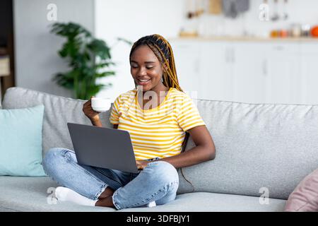 Schöne schwarze Frau auf der Suche nach Film online, Tee trinken Stockfoto