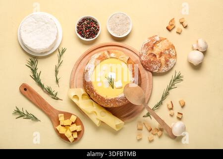 Käsesuppe in Brotschüssel mit Pilzen, Rosmarin und Croutons auf beigefarbenem Hintergrund Stockfoto