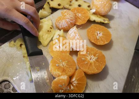 Gesunder Koch schneidet frische saftige Orangenscheiben auf Weißtafel für köstliche Morgensaftgetränke Stockfoto