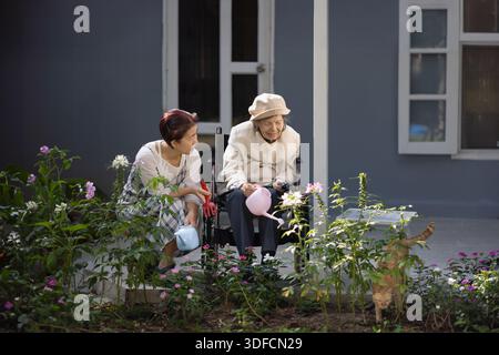 Ältere Frau im Garten mit Tochter und Katze. Stockfoto