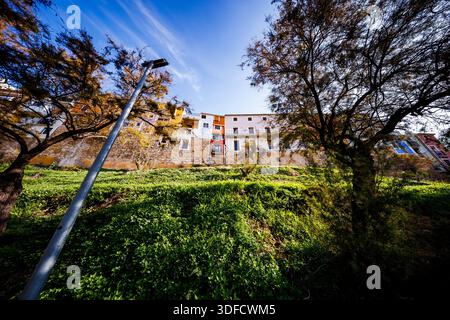 Eine von Bäumen eingerahmte, flache künstlerische Aufnahme, die die farbenfrohen Hängehäuser der Altstadt an einem tiefen blauen Himmel an einem hellen Tag zeigt. Stockfoto