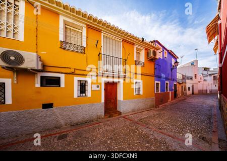 Ein Blick auf die angrenzenden lebhaften gelben und violetten Häuser mit typisch spanischen Fensterläden und gepflasterten Straßen im historischen Zentrum. Stockfoto