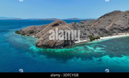 Atemberaubende Luftfahrt von Sebayur Island im Komodo Nationalpark, Indonesien. Trockene Hügel tauchen in eine türkisfarbene Lagune ein, weißer Sand trifft auf tiefblaues Meer Stockfoto