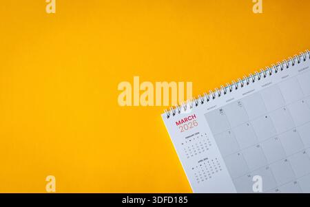 März 2026 Kalender auf gelber Oberfläche. Draufsicht, Kopierraum. Stockfoto