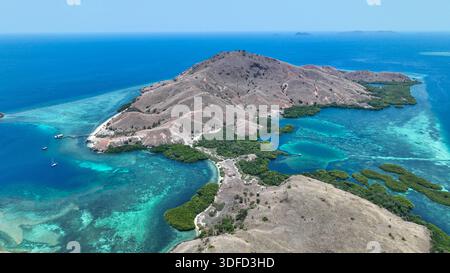 panoramablick auf Sebayur Island Besar, Komodo Nationalpark. Savannengipfel umschließen pulsierendes türkisfarbenes Wasser, Mangroven säumen Buchten mit weit entfernten Inseln Stockfoto