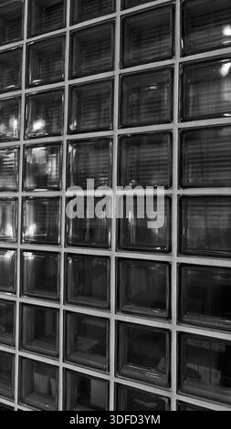 Elegante dunkle Glasblockwand mit Gittermuster und dezenten Reflexen. Die raffinierte architektonische Mattglasziegelstruktur ist perfekt für die Moderne Stockfoto