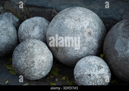 Steinkanonenkugeln aus der osmanischen Ära, die historische militärische Macht und antike Munition zur Belagerung in verschiedenen Größen und Texturen zeigen Stockfoto