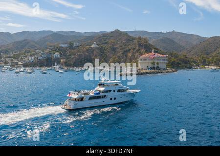 Aus der Vogelperspektive einer Luxusyacht, die durch das türkisfarbene Wasser in Richtung des ikonischen Casino-Gebäudes im Hafen von Avalon, Avalon, Kalifornien, Unit fährt Stockfoto