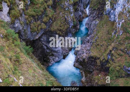 Blick von oben auf einen türkisfarbenen Tauchpool, der von einem Bergbach in einer engen felsigen Schlucht gebildet wird. Stockfoto