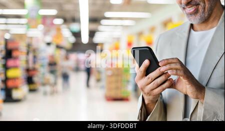Glücklicher Mann, der beim Online-Einkauf mit Lieferapp am Telefon steht. Stockfoto