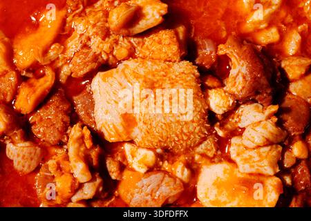 Ein Blick aus der Nähe auf Callos, ein bekanntes spanisches Gericht, das mit Kutteln aus Rindfleisch zubereitet und in einer scharfen roten Sauce gekocht wird und die rustikalen Zutaten und hervorhebt Stockfoto