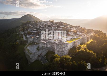 Blick aus der Vogelperspektive auf die alten Steinmauern von Berat Castle und die malerische Stadt im Inneren, umgeben von goldenem Sonnenlicht, Berat, Qarku i Beratit, Albanien. Stockfoto