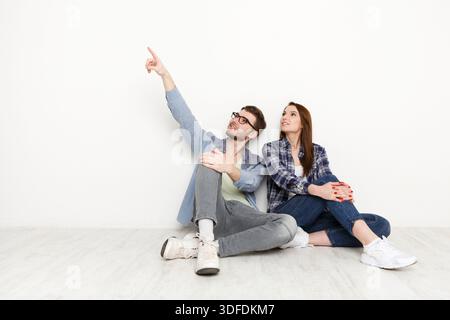 Ein Paar bewegt sich, sitzt auf dem Boden im leeren Raum Stockfoto