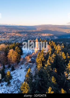 Der Stepanka-Aussichtsturm steht hoch im Isergebirge, wenn die Sonne untergeht. Der schneebedeckte Boden und die Bäume umgeben den Turm. Besucher genießen die Landschaft vom Aussichtspunkt aus. Stockfoto