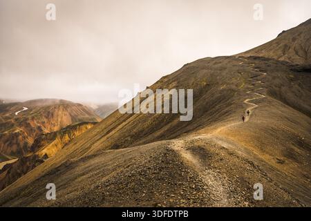 Blick auf einen gewundenen Pfad, der sich durch einen zerklüfteten, felsigen Bergrücken unter einem bewölkten Himmel zieht, ein Zeugnis der Pracht der Natur, Landmannalaugar, Central Stockfoto
