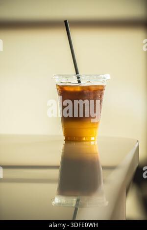 Eiskaffee-Getränk mit schwarzem Kaffee, das über Orangensaft gelegt und in einer klaren Tasse zum Mitnehmen über Eis serviert wird. Stockfoto