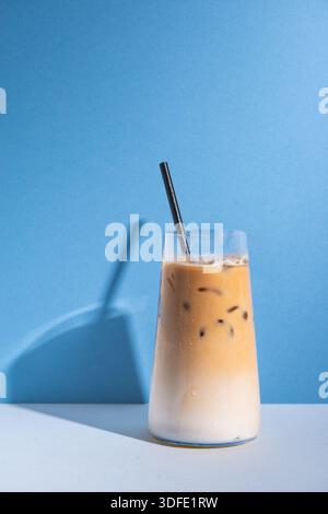 Eiskaffee serviert über Eis in einer klaren Glasschale. Cremiges Kaffeegetränk, fotografiert auf einem sauberen, minimalen Studiohintergrund, ideal für Cafés-Menüs. Stockfoto