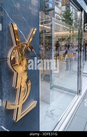 Tokio, Japan - 09. August 2025: Goldenes YSL-Logo auf der Außenfassade des Luxusgeschäfts, das die Straßenreflexionen in einem lebhaften Viertel Ginza einfängt Stockfoto