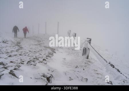 Winterstraße bergauf bei schlechtem Wetter. Reisende klettern die Straße bergauf Stockfoto