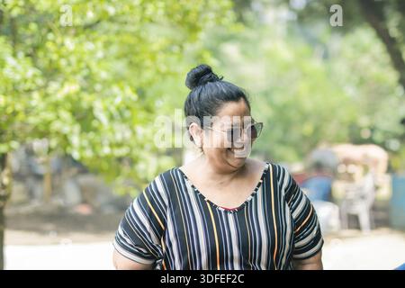 Porträt einer glücklichen Dame mit Brille draußen. Porträt einer glücklichen Dame in Übergröße mit Brille an einem sonnigen Tag Stockfoto