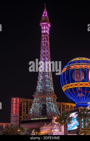 Der Blick auf den Nachbau des Eiffelturms erhebt sich am Nachthimmel und leuchtet mit rosa und blauen Lichtern neben einer hellblauen Heißluftballon-Attraktion, Las Vegas Stockfoto
