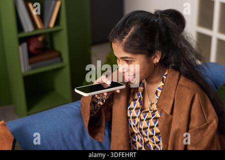 Junge Südasiatische Frau Mit Smartphone Voice Assistant In Innenräumen Stockfoto