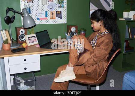 Junge südasiatische Frau, die im Home Office per Fernzugriff mit einem Laptop arbeitet Stockfoto