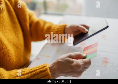 Seniorin beim Online-Shopping mit Smartphone und Kreditkarte Stockfoto